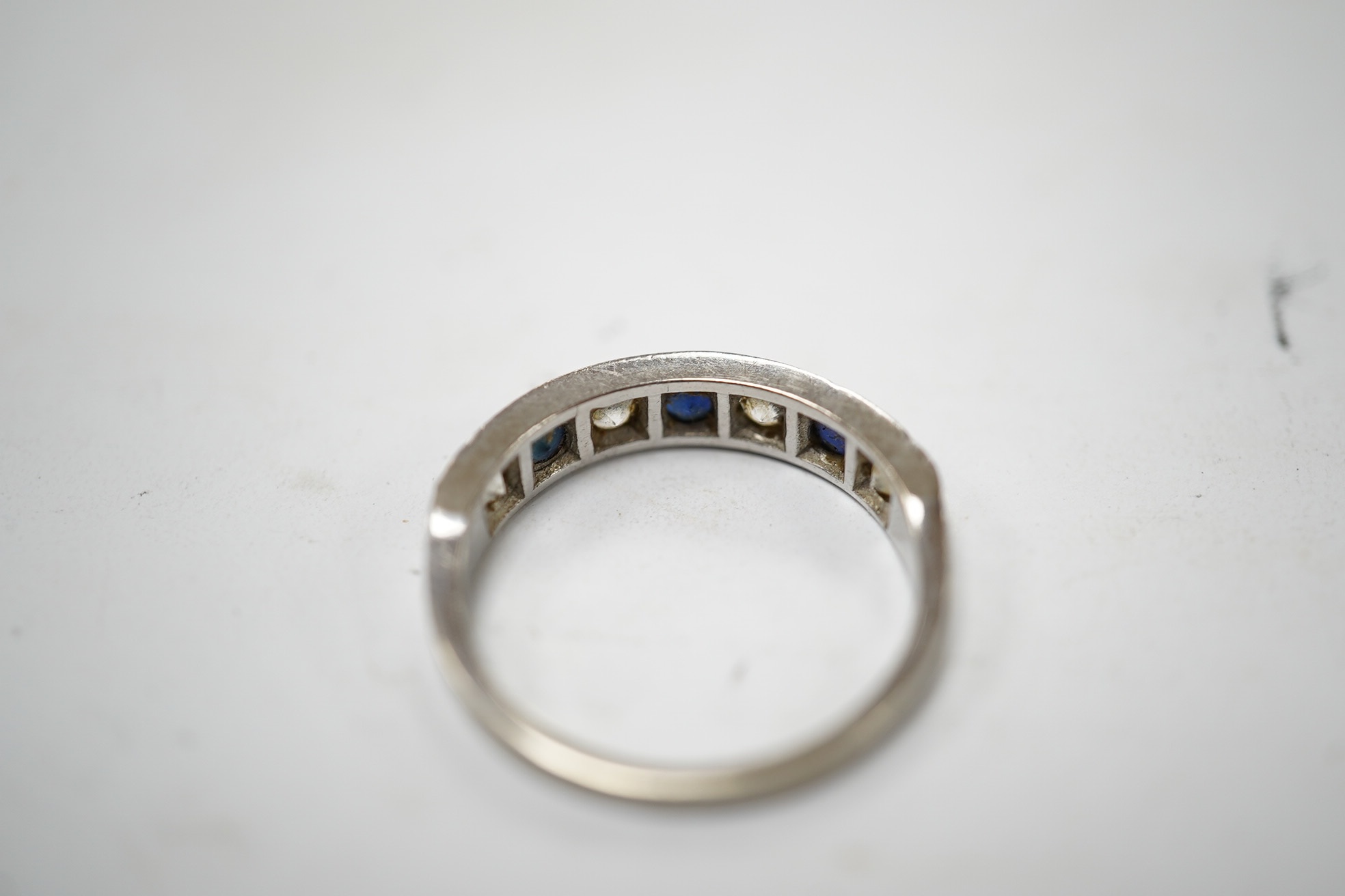 A 1970's 18ct white gold, sapphire and simulated diamond set half hoop ring, size O, gross weight 3.5 grams. Condition - fair